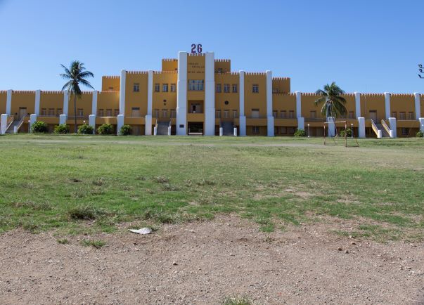The large yellow building called Moncada Barracks, with white details, on a clear day with blue skies. 