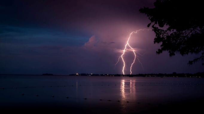 A clear photo of lightning from the clouds hitting the sea in a distance on a dark night outside Negril Jamaica