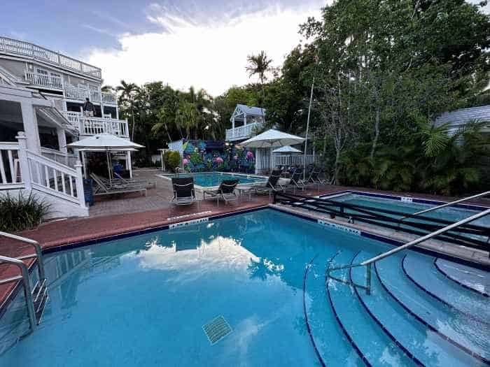 The beautiful blue pools in NYAH: Not Your Average Hotel in Key West in the backyard surrounded by green trees and the charming white wooden buildings