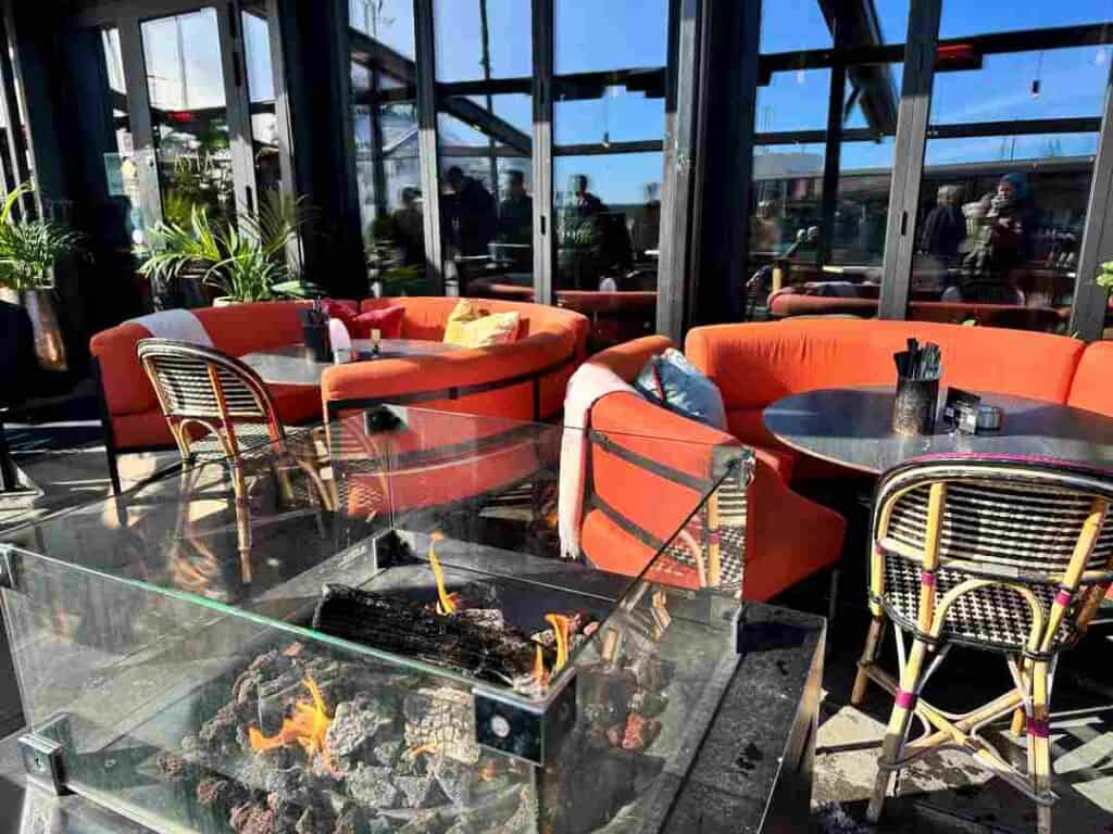Cozy outdoor seating at Aker Brygge in Oslo, red sofas and outdoor fire where people are seated most of the year despite the below zero temperatures. The photo is taken on a bright winter day with sun. 