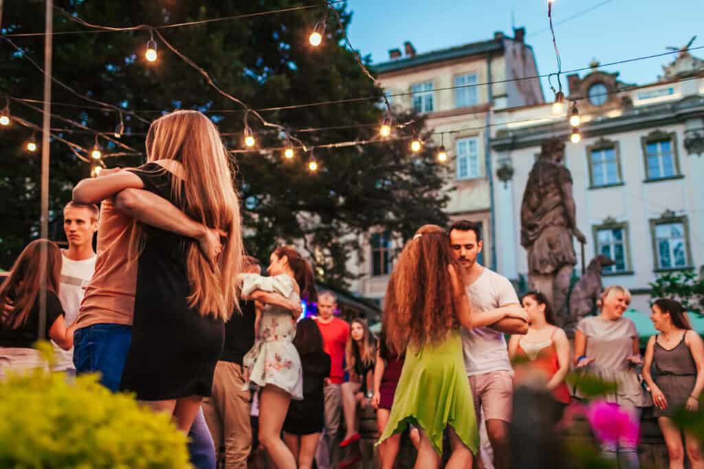 Couples dancing the kizomba on an outdoors square in Lviv, Ukraina, on a wrm summer nights with beautiful lights hanging overhead. 