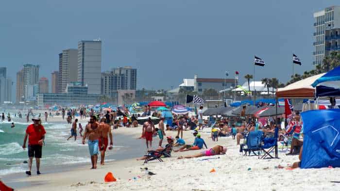 High season on the white sands of Panama City Beach with hundreds of people, colorful parasols, beach flags, and vibrant life - some would call this too crowded. 
