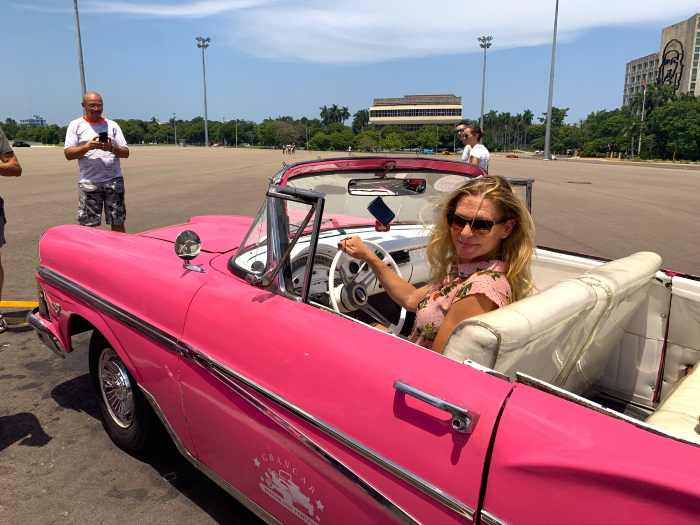 Pink convertivle classic American car with me in the driver seat on a bright sunny day in Havana