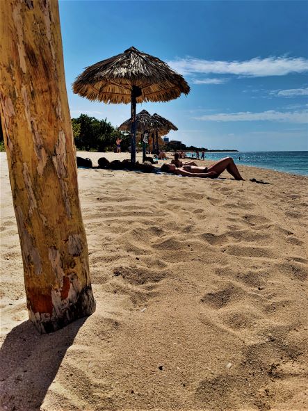 The golden sands of Playa Ancon outside Trinidad, people sun bathing on the soft warm sand