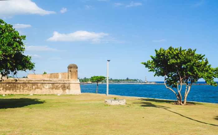 Punta Torecillas grassy field and small fortress structure on a sunny summer day in Santo Domingo