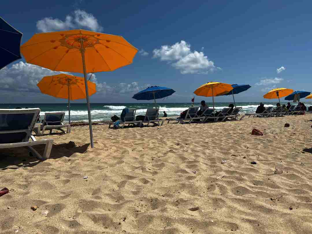 Playas del Este golden sands beach with sun loungers and parasols in blue and orange aganist the waves and blue sky