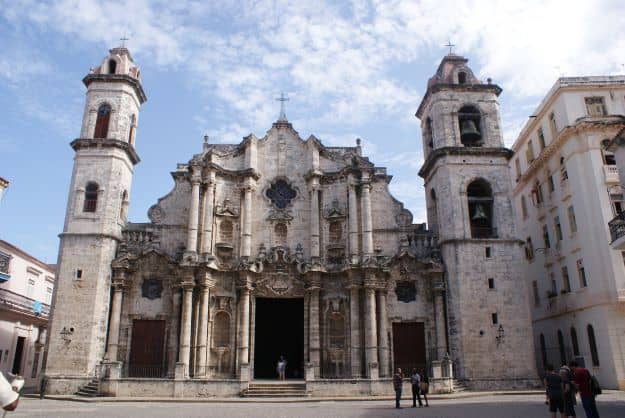 Photo of the facade of the Havana Cathedral in grey stone with lots of ornate details, columns, and towers. 