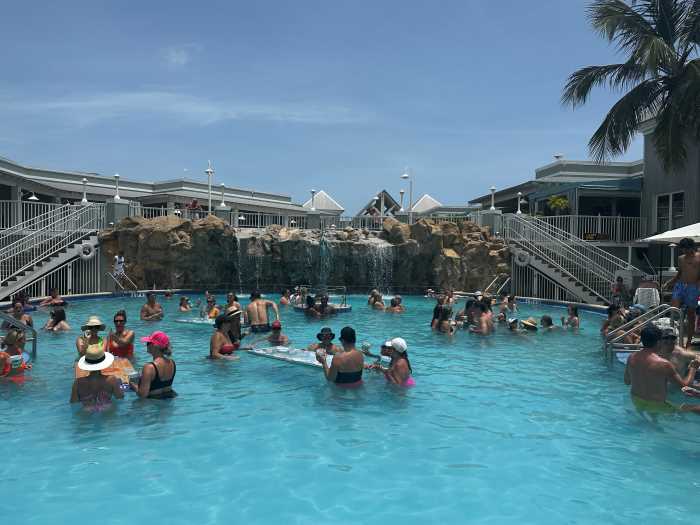A bar that also has a pool in Key West, making it a pool-bar-party venue under the blue skies with music playing and lots of party-people in the blue pool