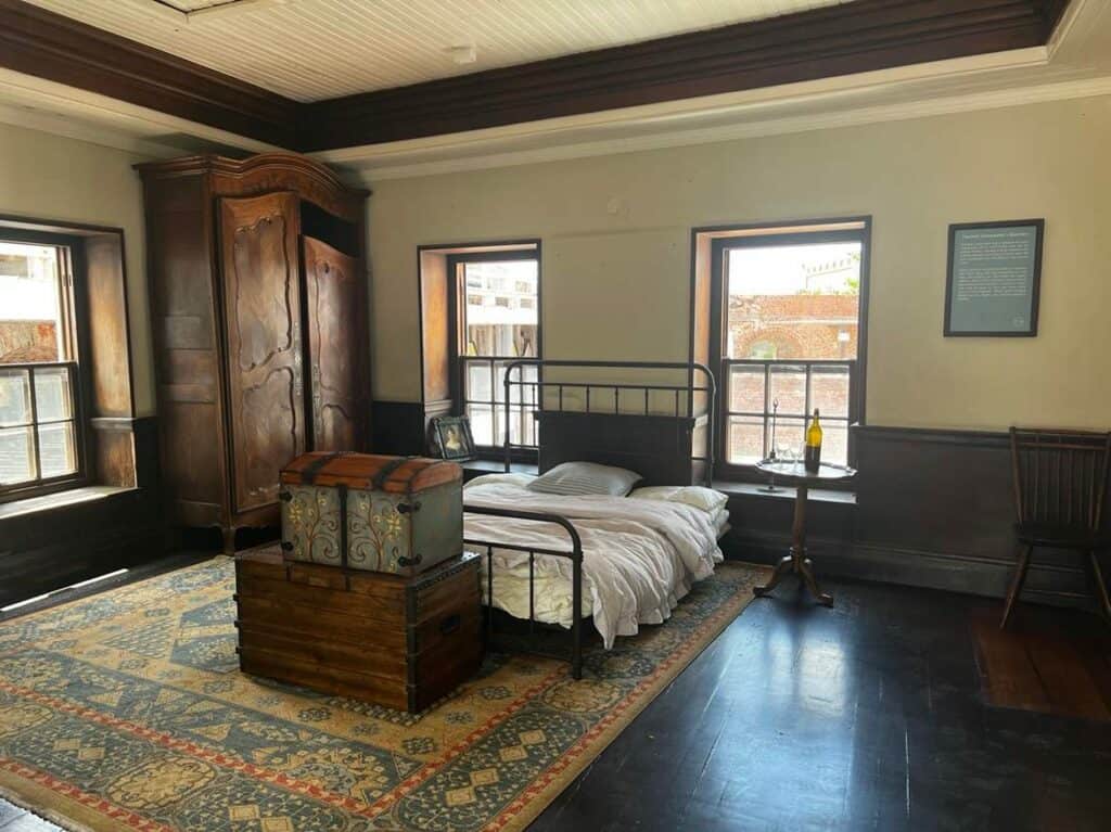 From an old officers quarter in Port Rotal, with shiny dark wooden floors, decorative windows, a double bed, and decorated wooden boxes for storage on a large colorful oriental carpet. There is even a bottle of wine on the bedside table!