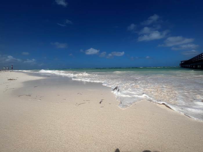 The white sands and soft surf from the sea on Punta Cana beach on a bright sunny summer day
