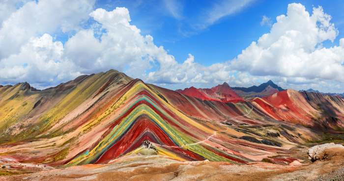 The fascinating rainbow mountain in Peru, with intertwining lines in all colors like red, yellow, pink, orange, green, and even grey and black. 