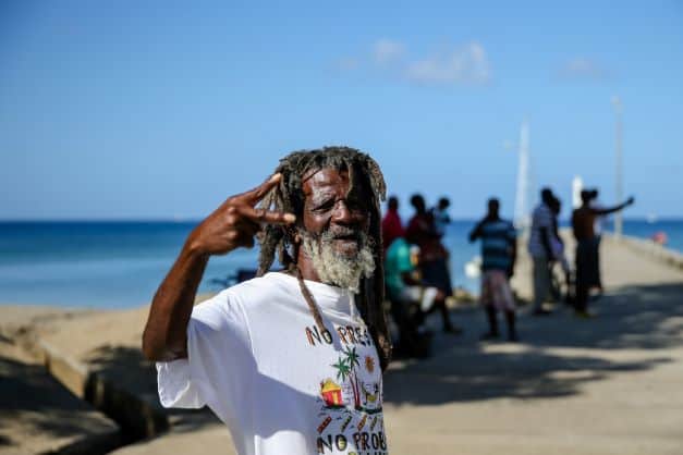 A happy smiling rastafari in Jamaica, wearing a white t-shirt and long grey beard on a bright sunny day seaside in Jamaica