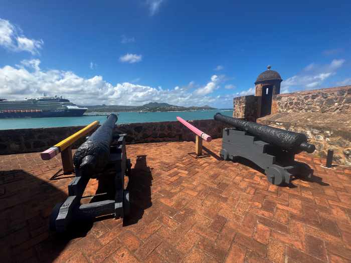 Old cannons on maroon brick floors in San Felipa Fortress with a view of the sea and the cruise port in Puerto Plata on a sunny day