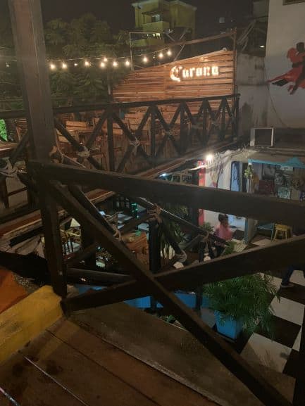 A charming restaurant in Santa Marta at night, photo taken from the second floor where you see down to the first floor with tiled floors, lights, and people. 