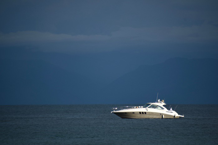 A Ray Sundance motor boat on the dark blue sea, shining white, with dark greyish blue skies in the background