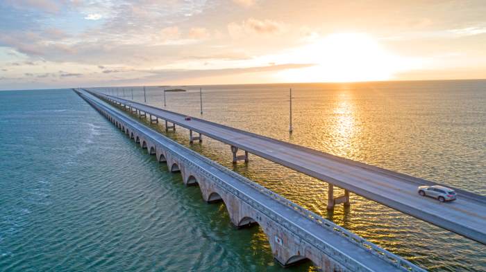 The almost infinite Seven Mile Bridge over to Marathon Key over the water around sunset, where the sun reflects the golden colors in the sea and the sky in the horizon
