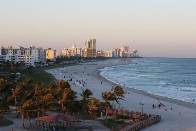 The southern part of South Beach in Miami early in the morning as the sun is about to rise, the sky and beach are pale waiting for the sun that has just reached the skyline in the far end of the photo