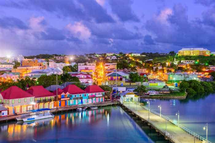 The port of St Johns at night, with a cloudy darkening sky above with warm lights coming from the colorful city scape