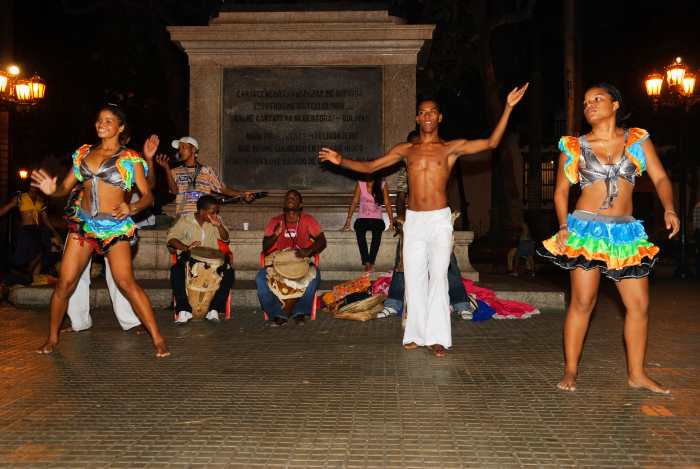 Street dancers in colorful costumes and musicians after dark in Cartagena