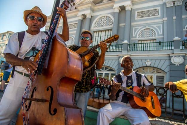 A band of smiling musicians with guitars and a huge contrabas in Santiago de Cuba on a sunny summer day
