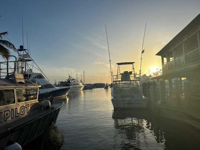 Sunrise over Key West Marina with silvery rays on the dark water between the boats under a pale blue sky