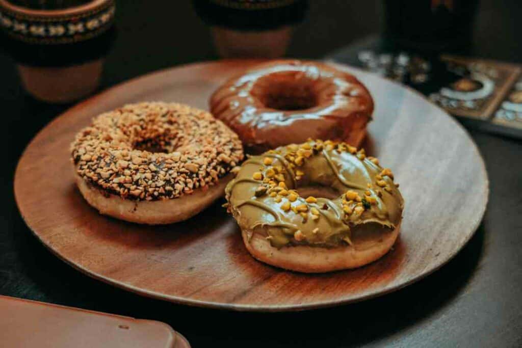Three tasty donuts with different topping on a wooden plate ready to eat! 