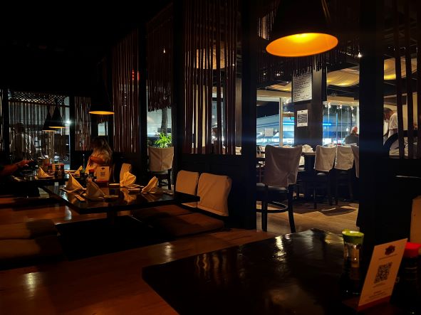 Sushi restaurant in Miami Beach, with low tables, a warm sparingly lit atmosphere at night, with warm lights and a cozy atmosphere