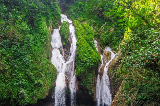Two tall narrow waterfalls amidst green forest and bushes in Topes de Collantes National Park in Cuba