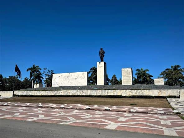 The huge statue of Che Guevara in Santa Clara, over his own mausoleum and last resting place. The statue is black against the blue sky, and the revolution square in front is decorated with colorful tiles. 