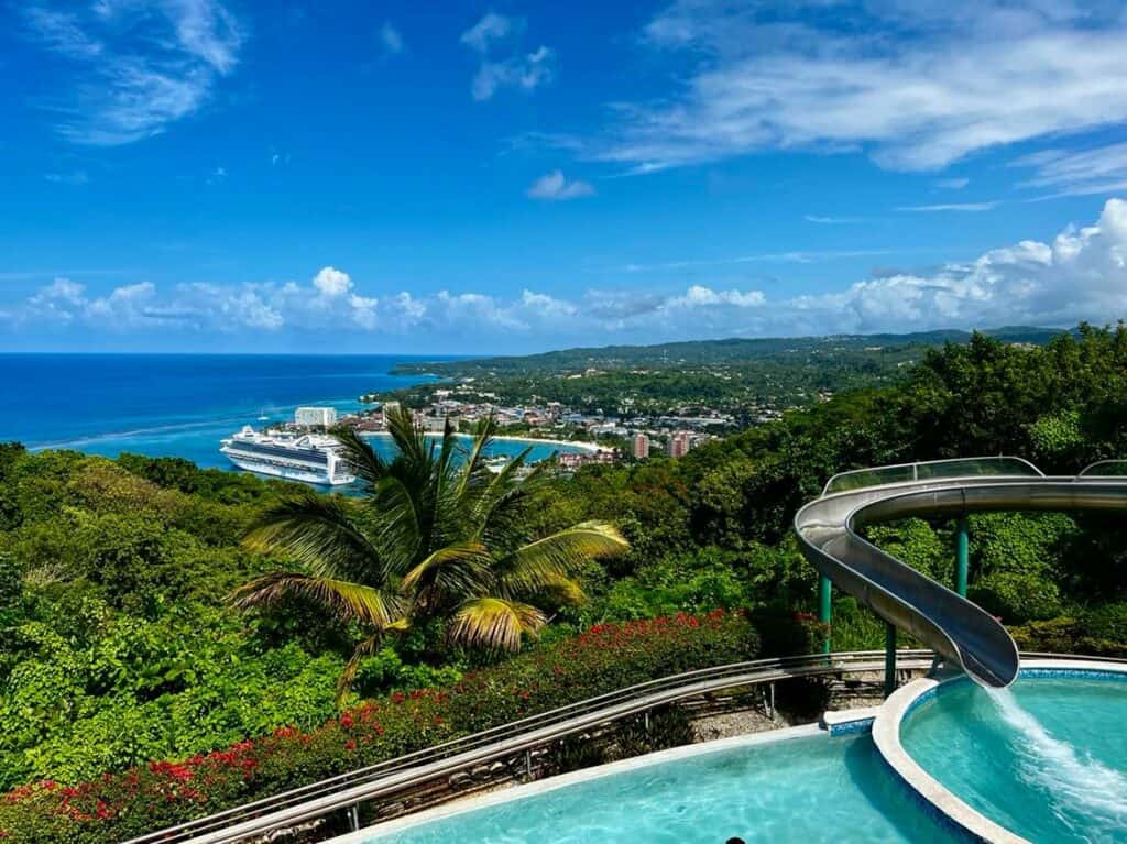 A bright sunny summer day on top of Mystic Mountain where there is a pool, and a spectacular view of Ocho Rios, the ocean, and the cruise port on the blue water