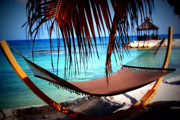 Chill in a hammock on the beach in Montego Bay, under the palm trees on the white sands by the blue crystal clear ocean. 