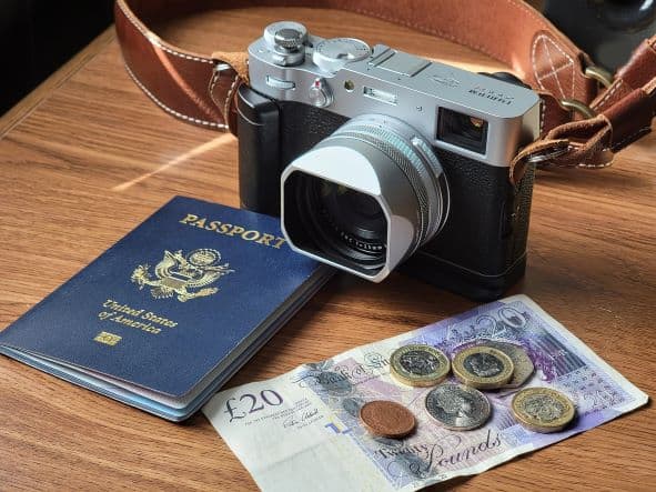How much money should I bring to Cuba illustratin photo: a camera, passport and cash sitting on a table. 