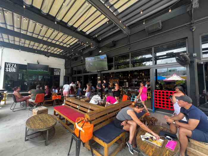 Charming outdoor seating groups at the Veza Sur microbrewery in Wynwood Miami, with a mix of colorful and wooden furniture and a laid back atmosphere