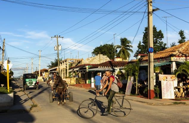 Street in Vinales with cars, horse and carrieges, bikers, restaurants and a myriad of electrical cords above on a bright sunny summer day