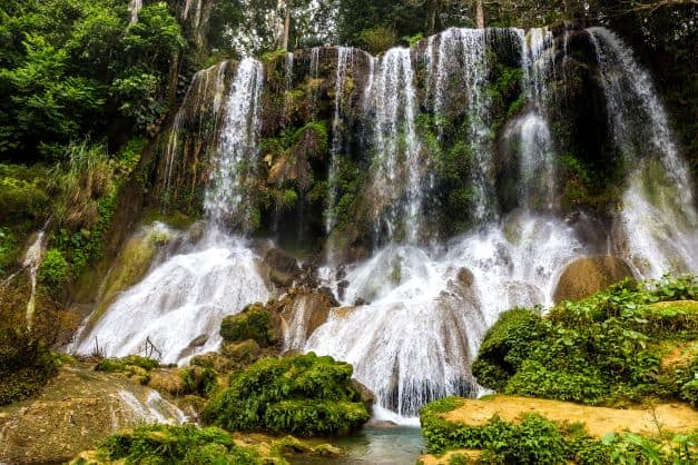 A beautiful waterfall in the middle of the forest with greenery on all sides in Topes de Collantes National Park in Cuba