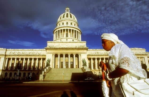 woman in all white clothes in front of the Capitolio on a bright summer day under a blue sky. 