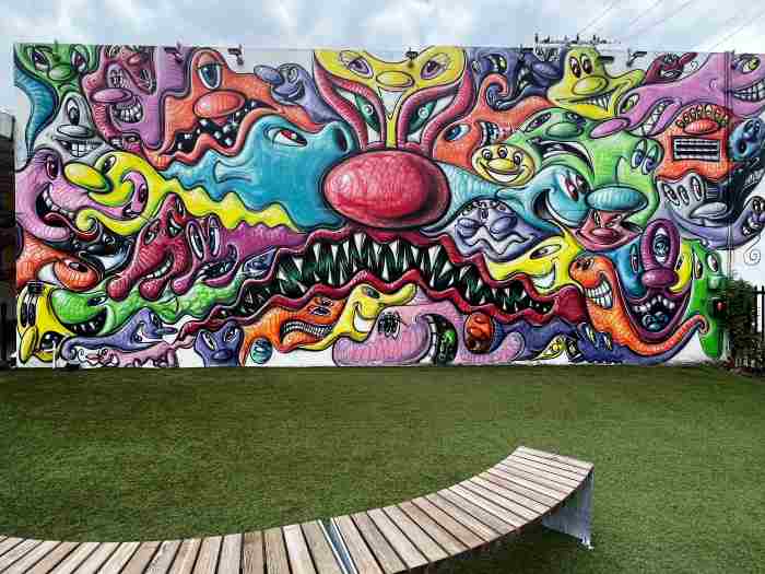 A colorful mural in Wynwood Walls, covering a whole outdoor wall with green grass and a bench to sit and admire it in the front