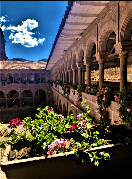 Flower decorations in a beautiful stone courtyard of several stories in Cuscu, the sun is shining and the sky is blue. 