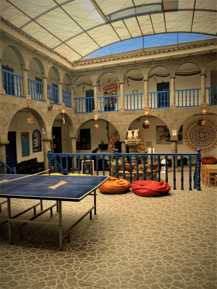 Inside courtyard hall at Cocopelli Hostel with high ceilings, elaborate arched walkways, a pingpong table and nice seating arrangments. 