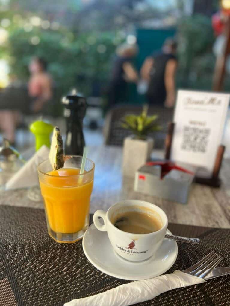 Close up photo of a Cuban coffee and fresh orange juice sitting on a wooden table at Bone Ma Paladar