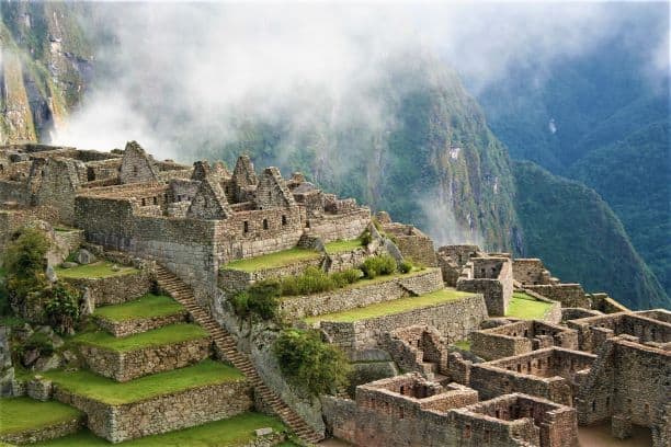 Ancient ruins in the mountains on the inca trail, with floating clouds and mountain sides in the background