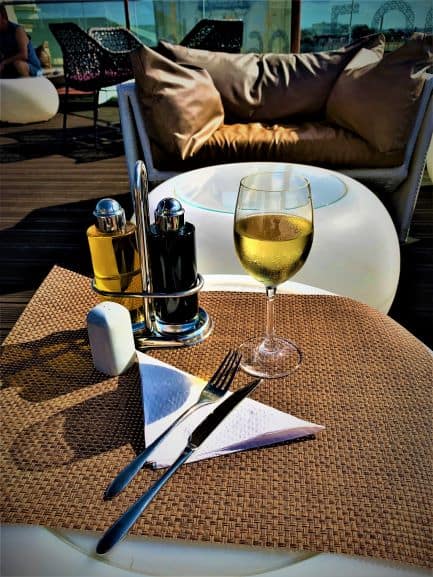 A glass of white wine on the table a sunny day on the rooftop terrace of Manzana Kempinski