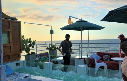 View of the ocean from Malecon 663 at sunset, in the photo front is the glass jacuzzi, and in the back the waiter is serving tables. 