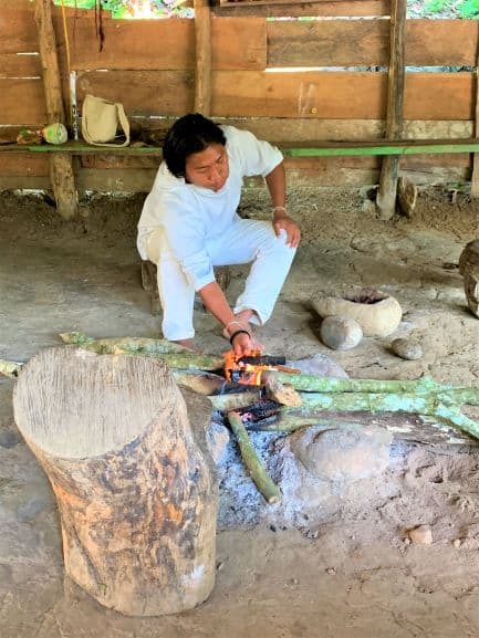 A man from the Wiwa tribe by the fire in a locan hut, wearing all white