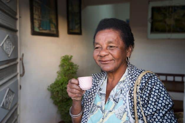 Cubans enjoy their cafecito! A woman smiling, having a small pink cup of coffee. 