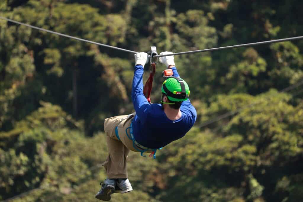 Man ziplining high above the green forest