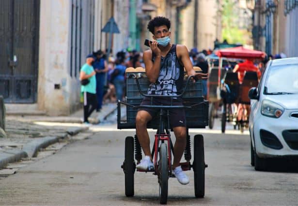 Bicycle transport guy on a three wheeler in Havana, transporting bread, in the middle of city traffic