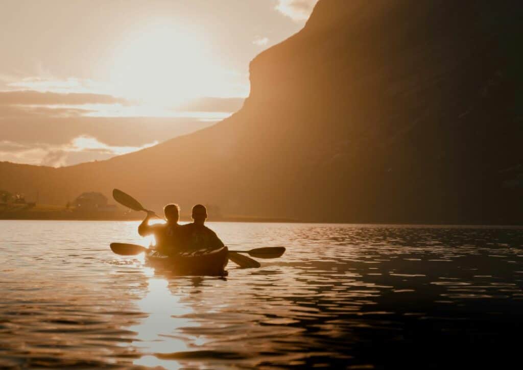 Kayaking in the low golden midnight sun under the mountains in Lofoten Norway
