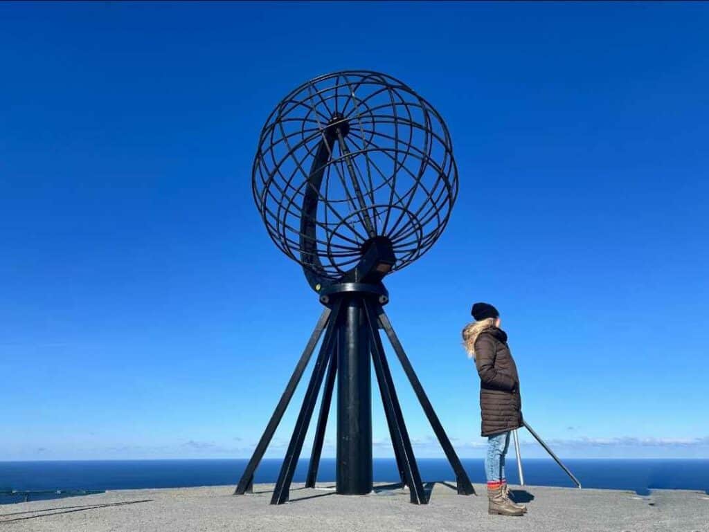 Me on the North Cape on a bright sunny day next to the famous globe under dark blue skies