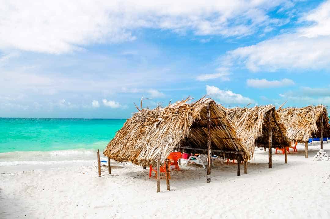 White sandy paradisiacal beaches in Isla Baru outside Cartagena Colombia, with straw huts to lounge under, and the beautiful greenish blue sea outside